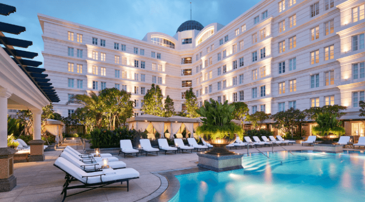 a pool with lounge chairs in front of a building
