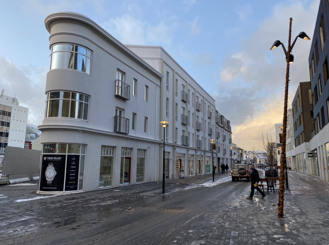 a street with a building and people walking on it