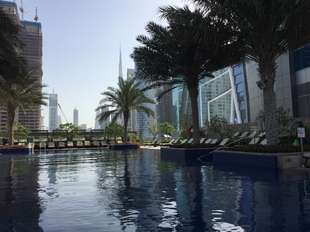 a pool with palm trees and a building in the background