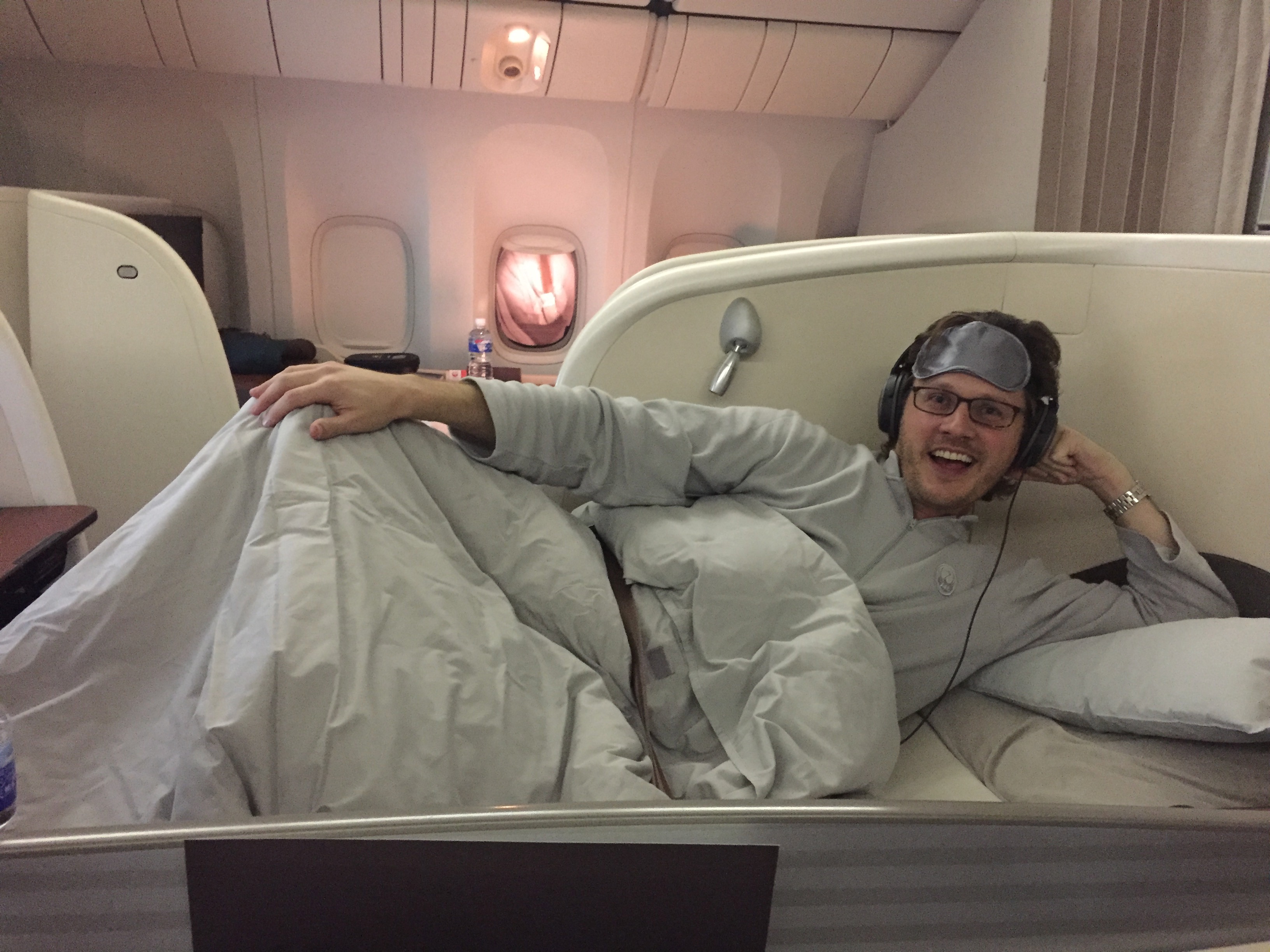 a man lying in a bed with headphones and a blanket