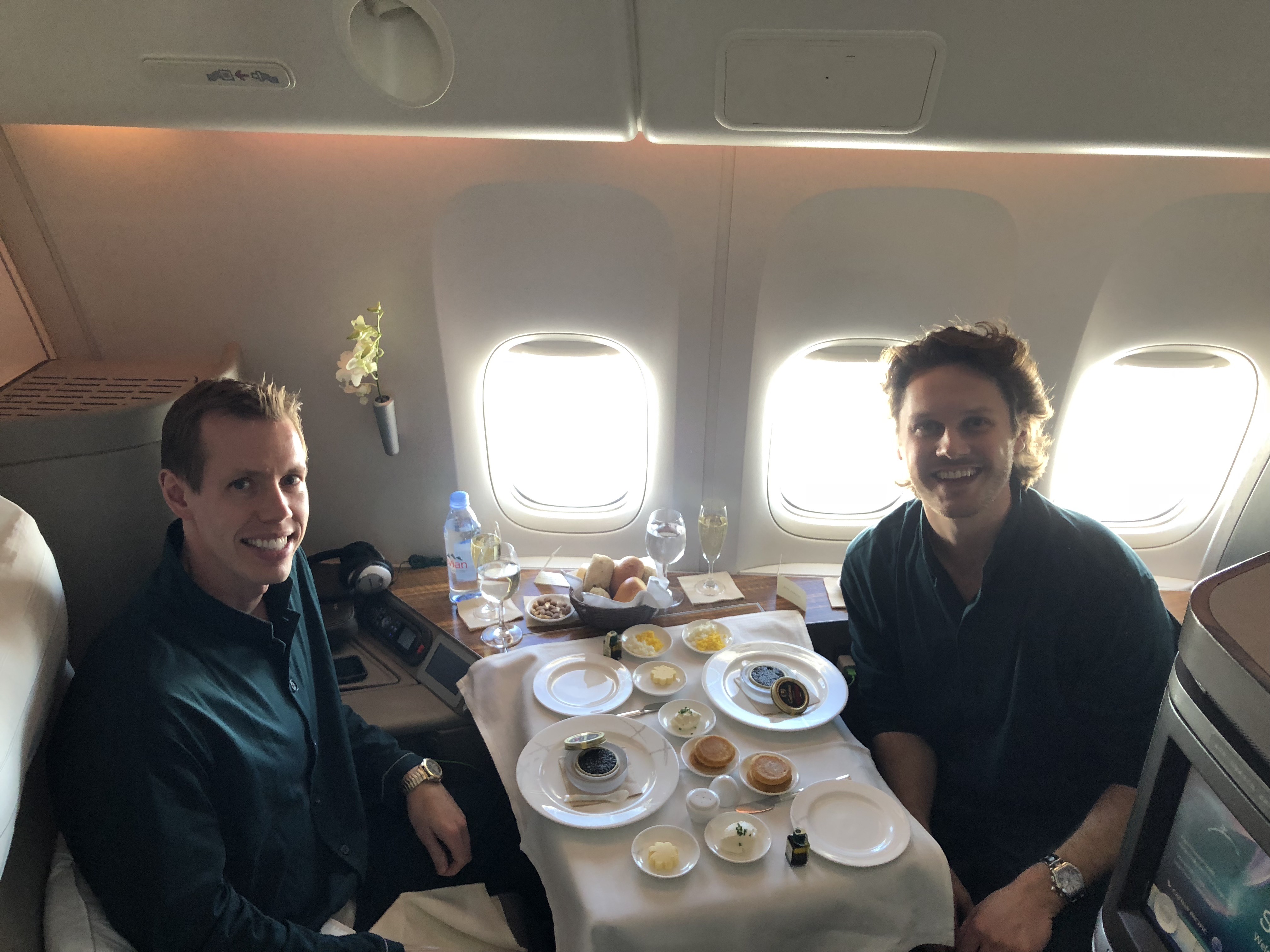 two men sitting at a table with food on it