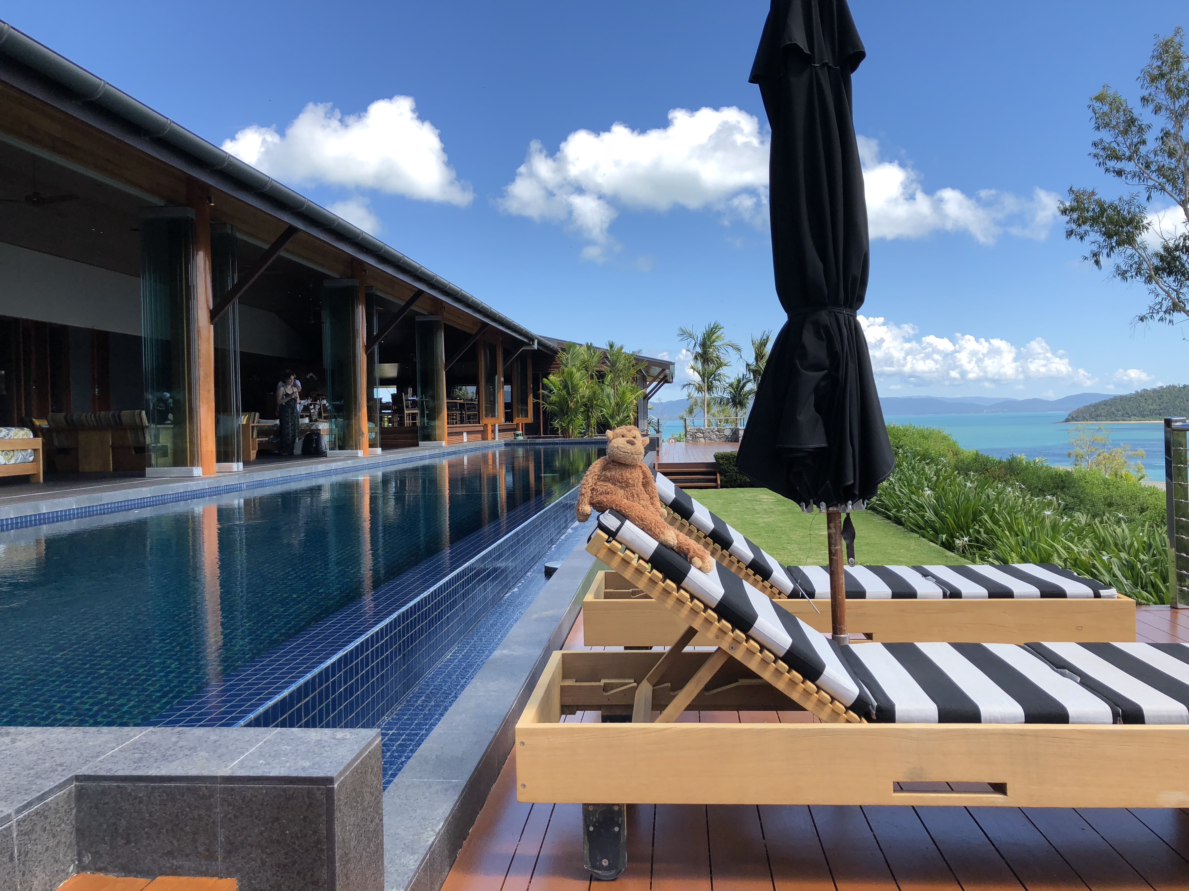 a teddy bear sitting on a lounge chair next to a pool