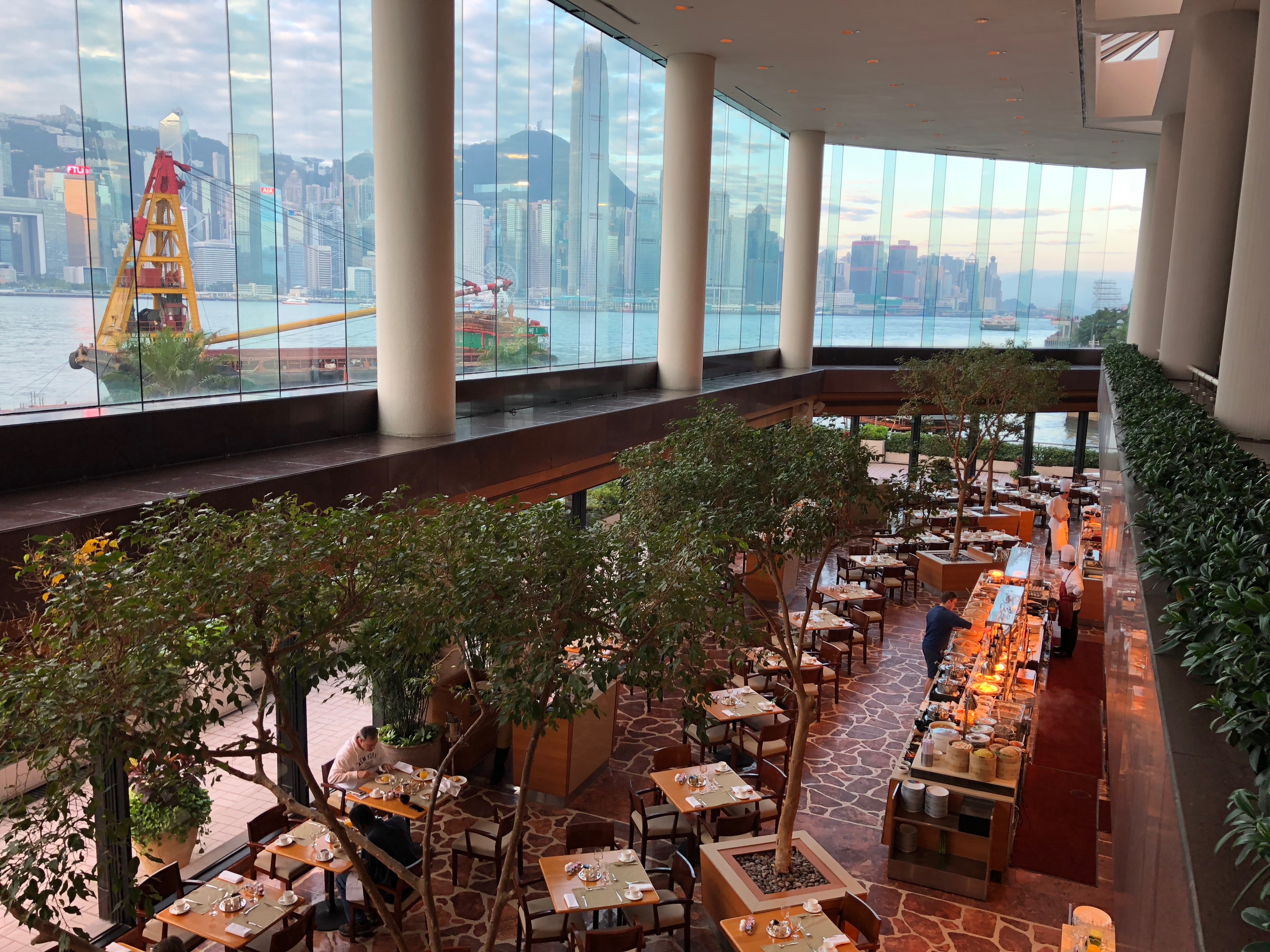 a large glass building with tables and trees