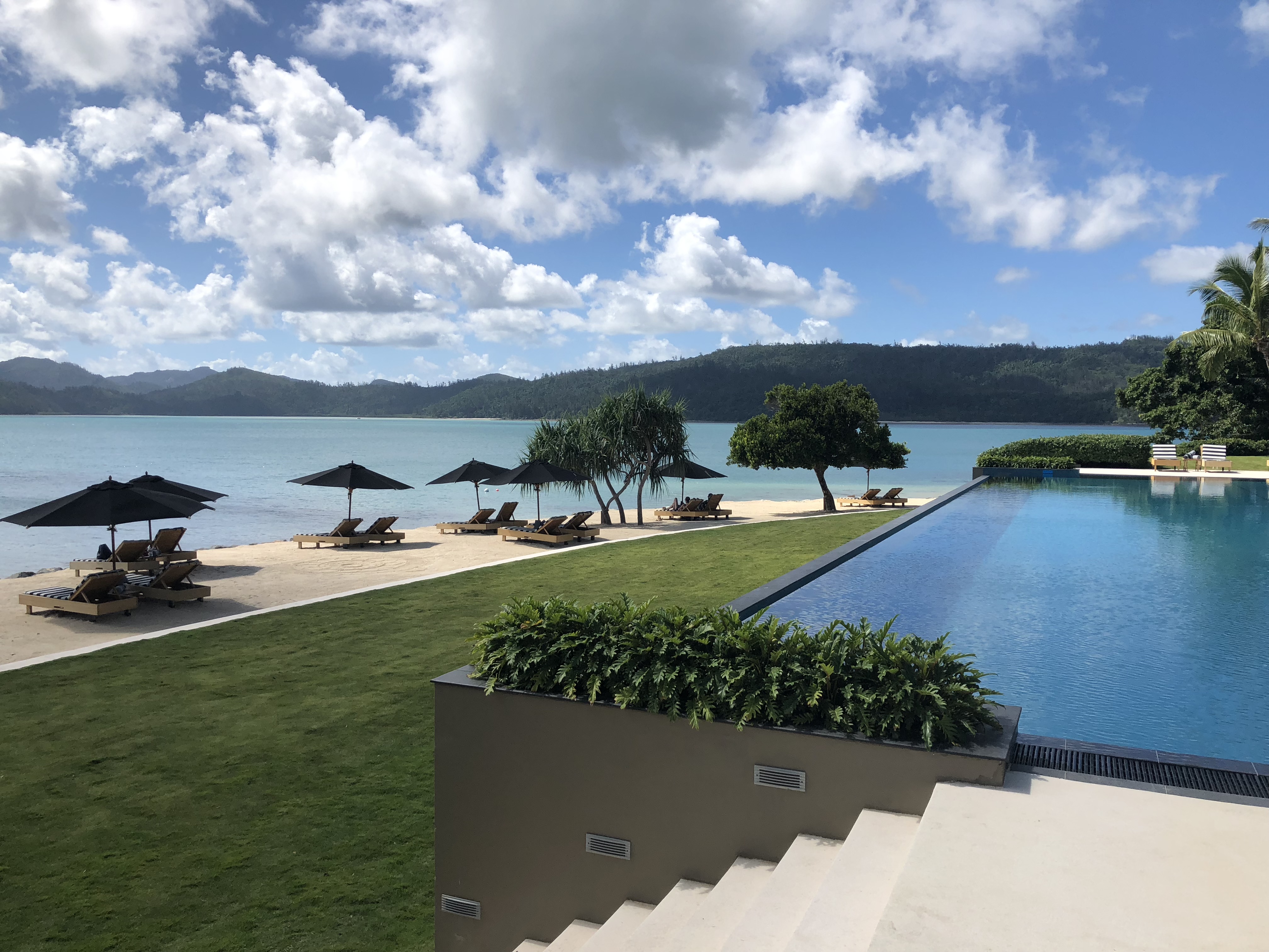 a pool with umbrellas and chairs by a body of water