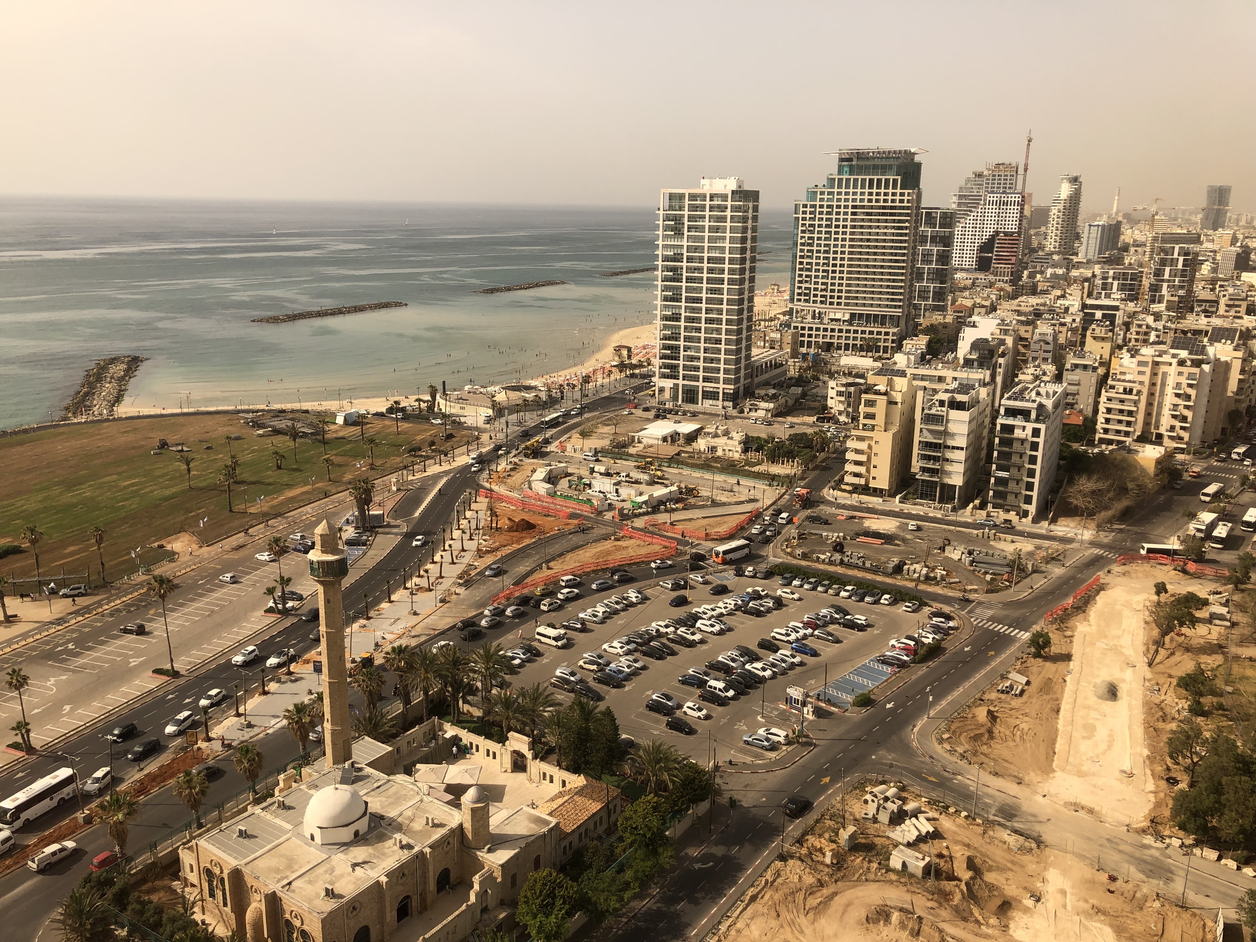 a city with cars and buildings on the beach