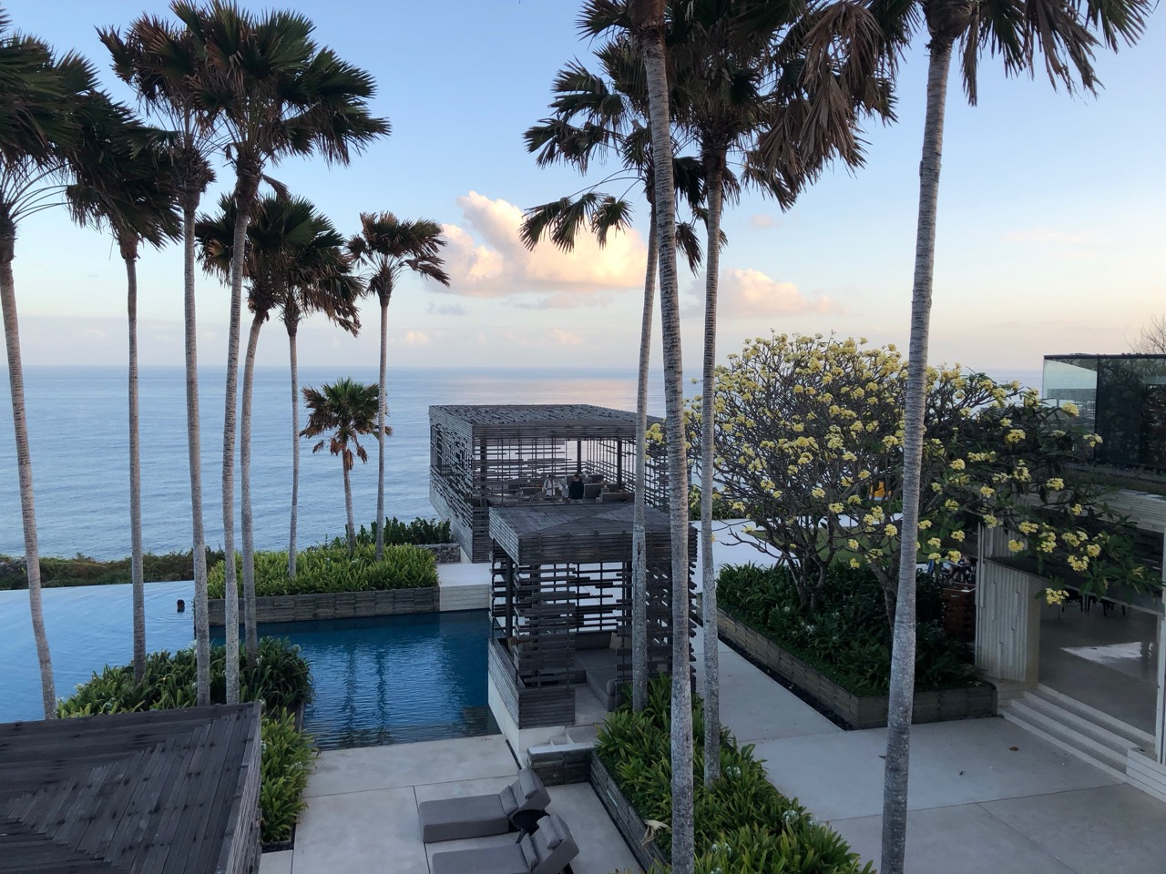 a pool with palm trees and a deck with a deck and a building with a body of water