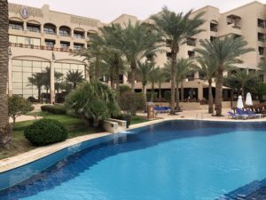 a pool with palm trees in front of a building
