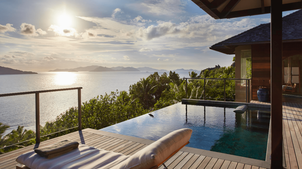a pool with a deck and a house overlooking the ocean
