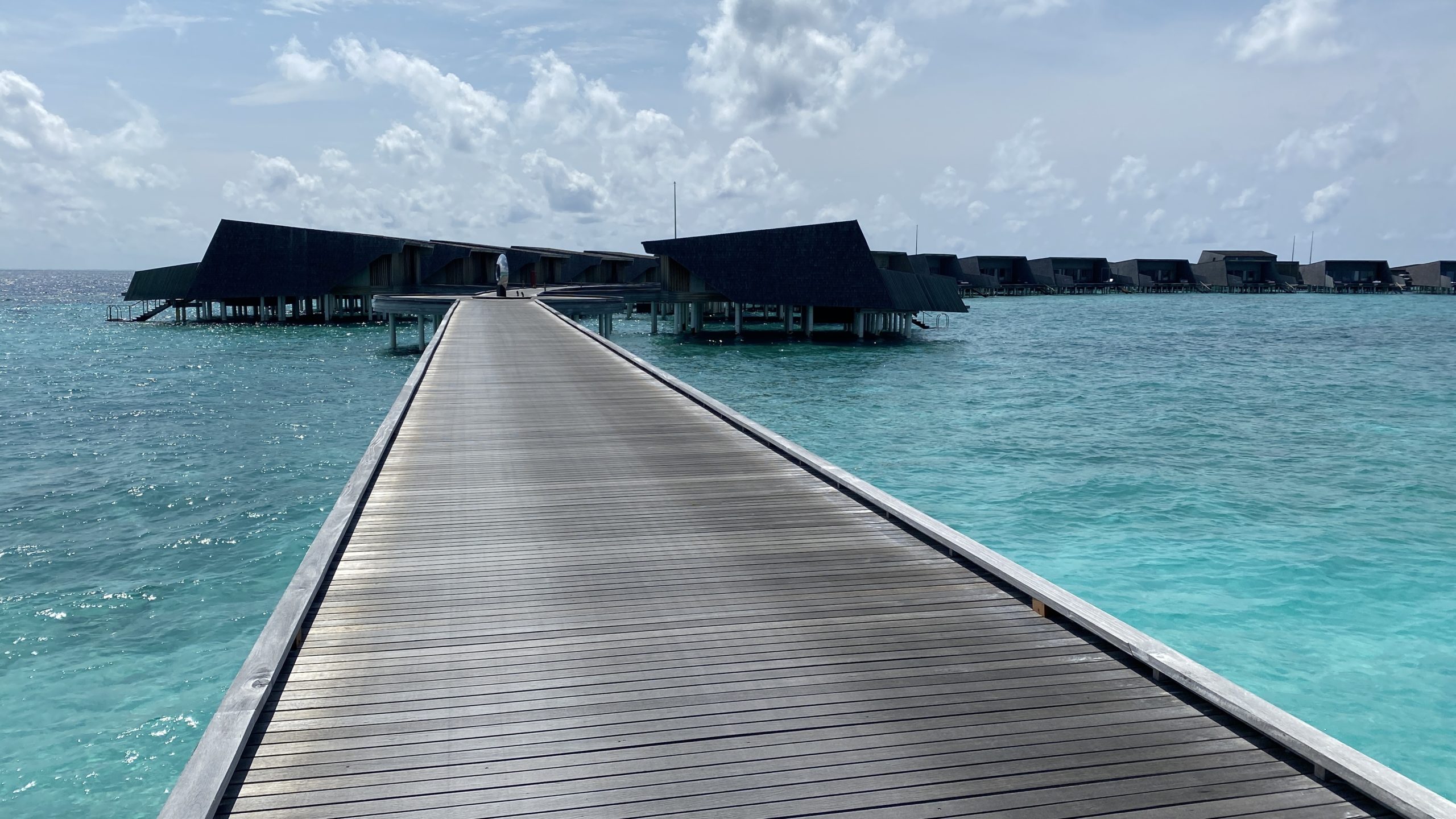 a long dock over water with buildings in the background