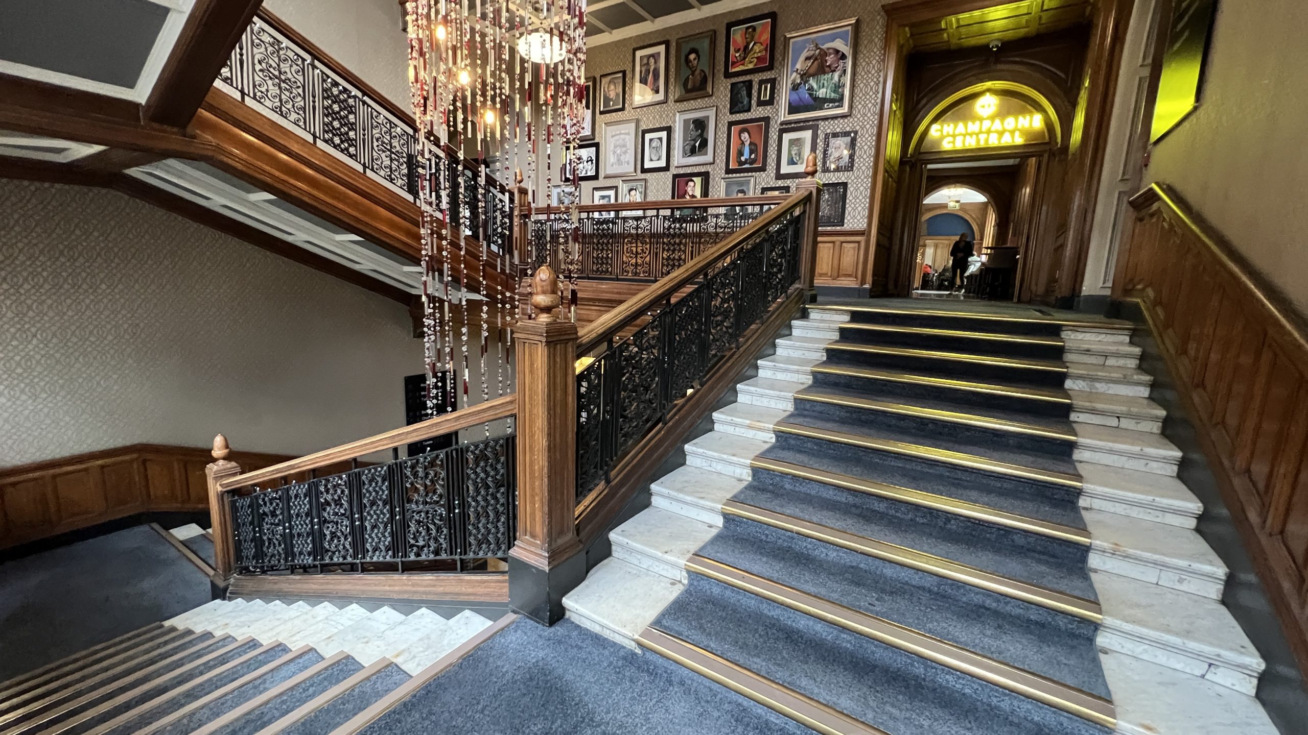 a staircase with a chandelier and pictures on the wall