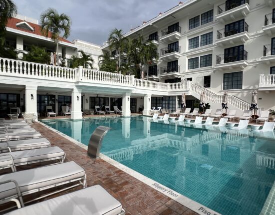 a pool with chairs and a building in the background