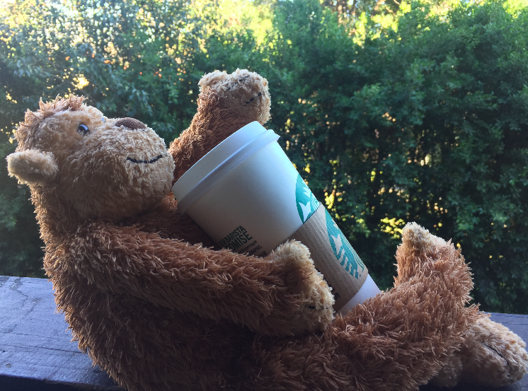 a stuffed teddy bear holding a coffee cup
