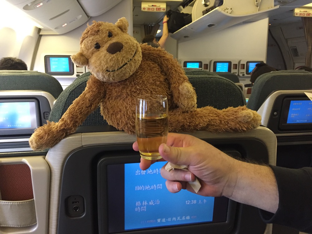 a hand holding a glass of liquid next to a stuffed animal