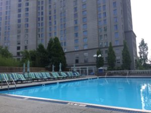 a pool with chairs and umbrellas in front of a building