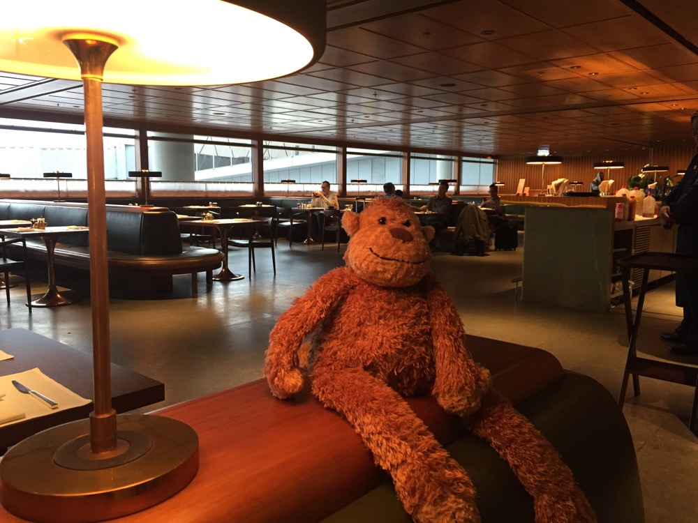 a stuffed animal sitting on a bench in a room with tables and chairs