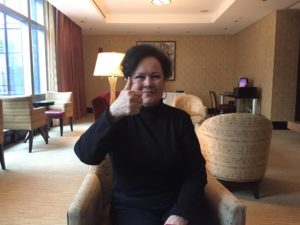 a woman sitting in a chair giving a thumbs up