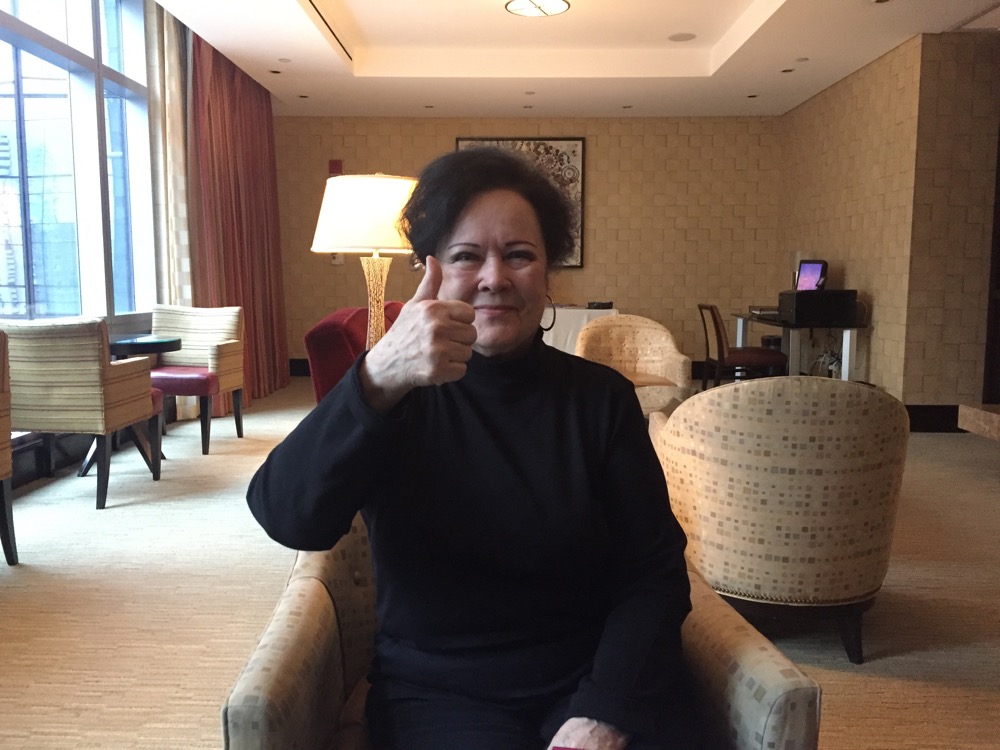 a woman sitting in a chair giving a thumbs up
