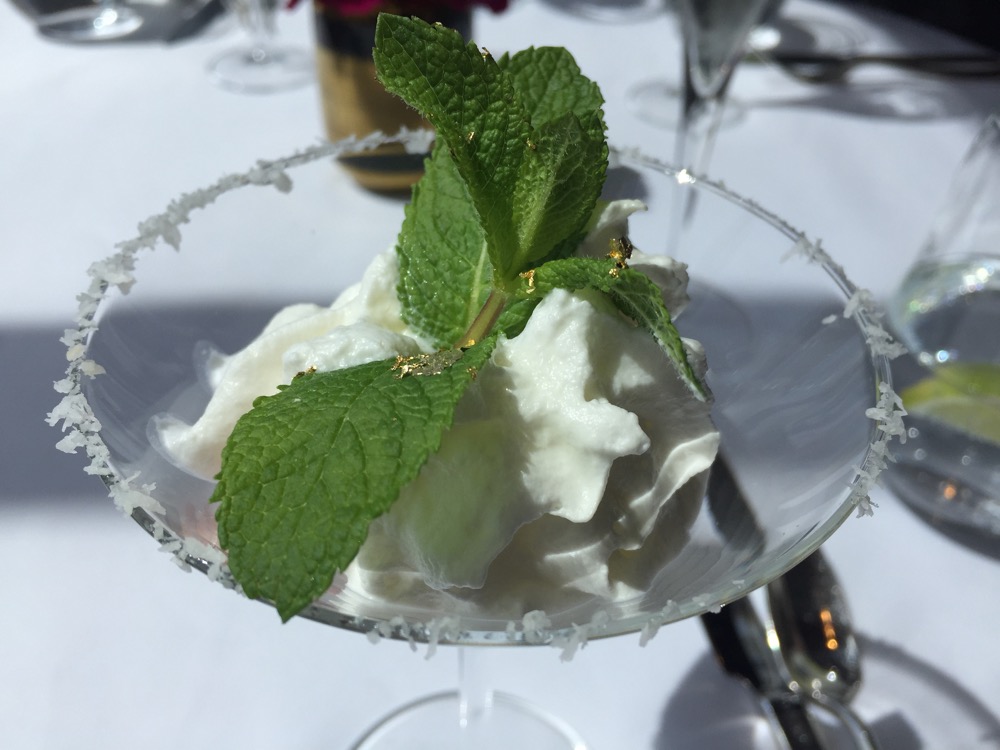a glass dish with whipped cream and mint leaves