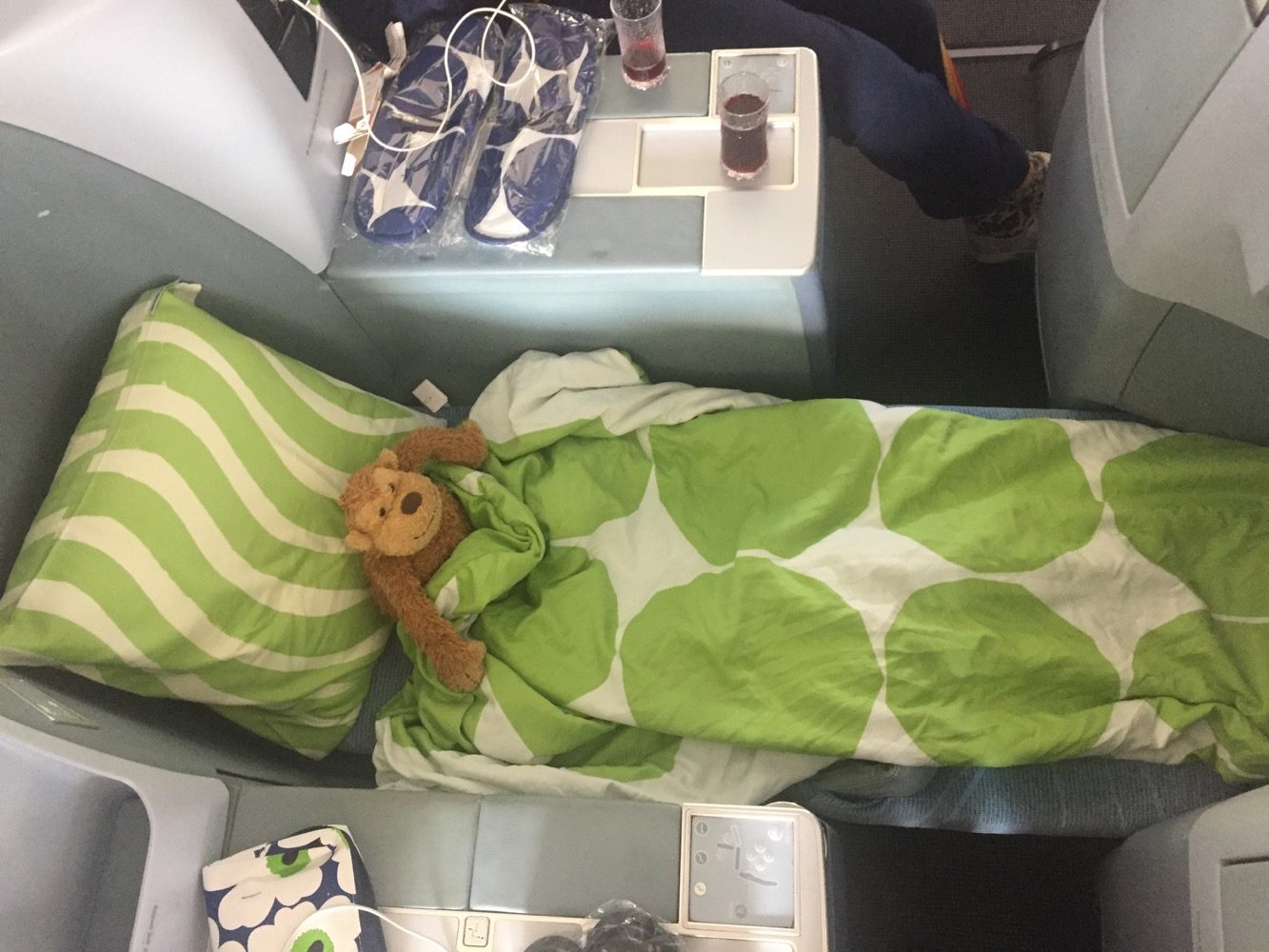a teddy bear wrapped in a blanket on a plane