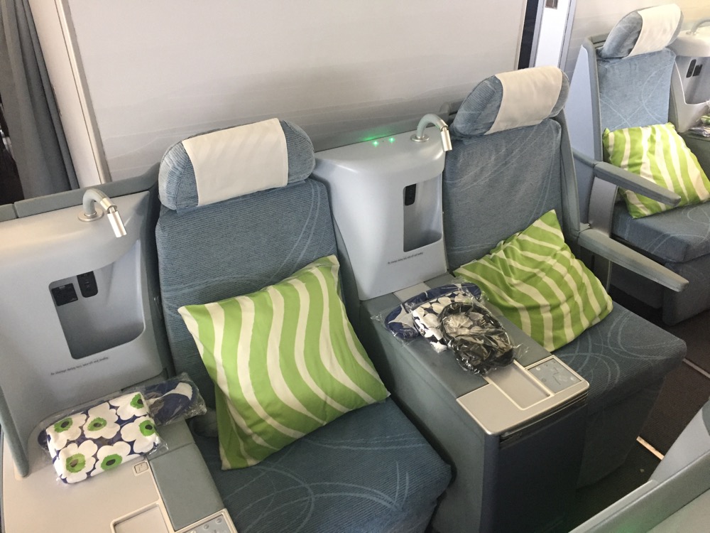 a row of seats with green and white pillows