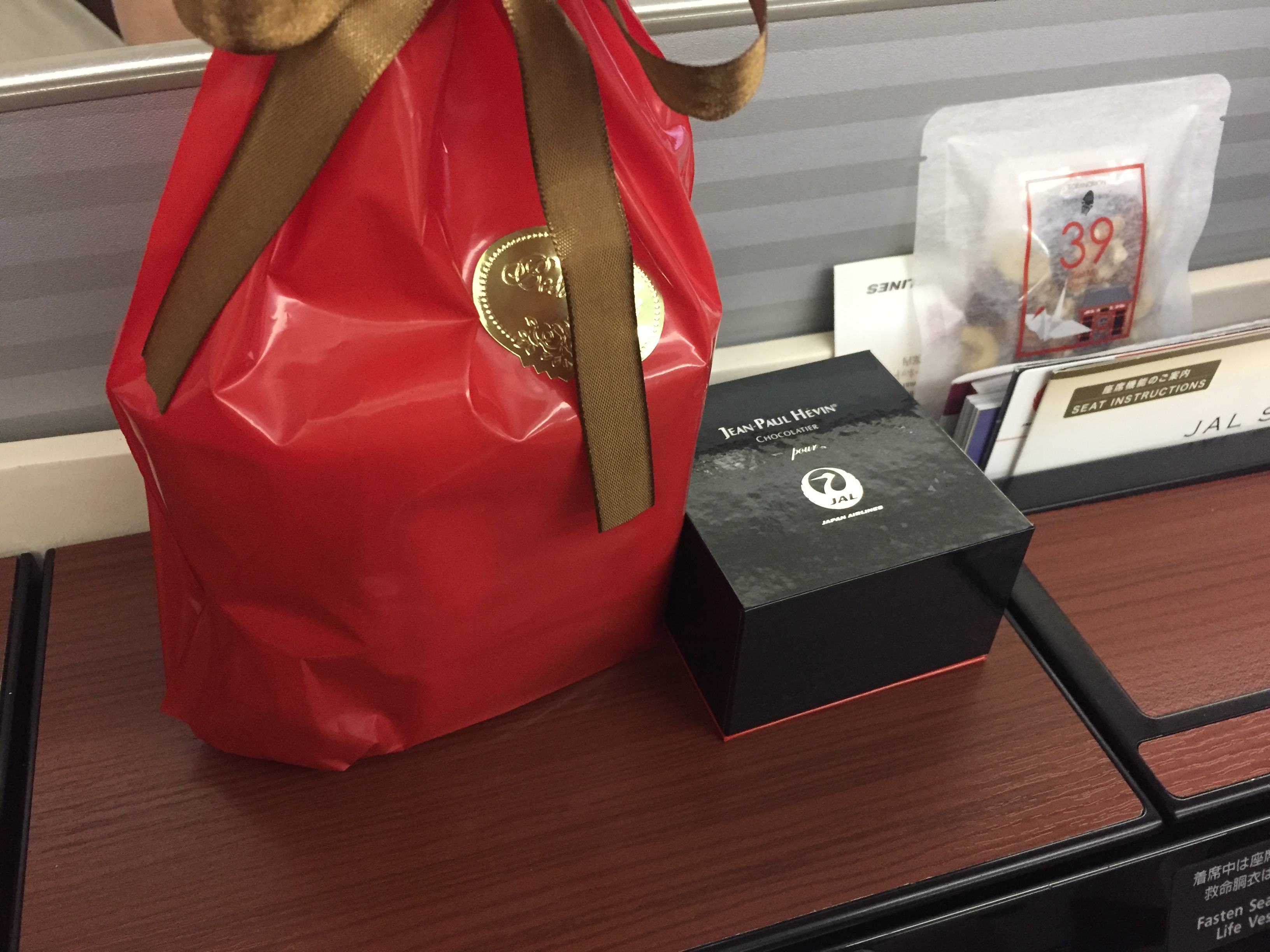 a red bag with a gold ribbon and a black box on a table