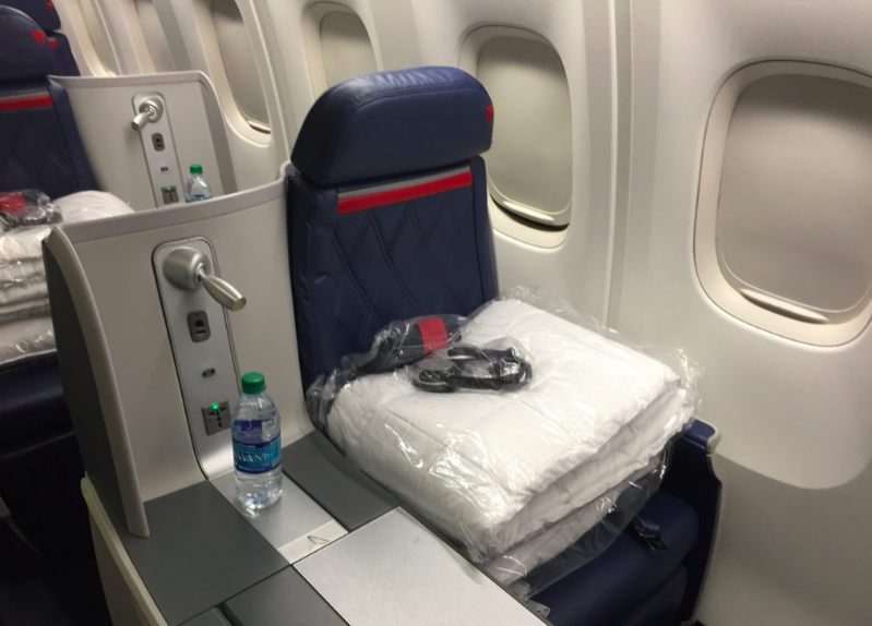 a seat with a white blanket and a bottle of water on the side of it
