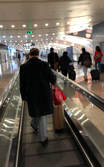 a man walking down an airport with luggage