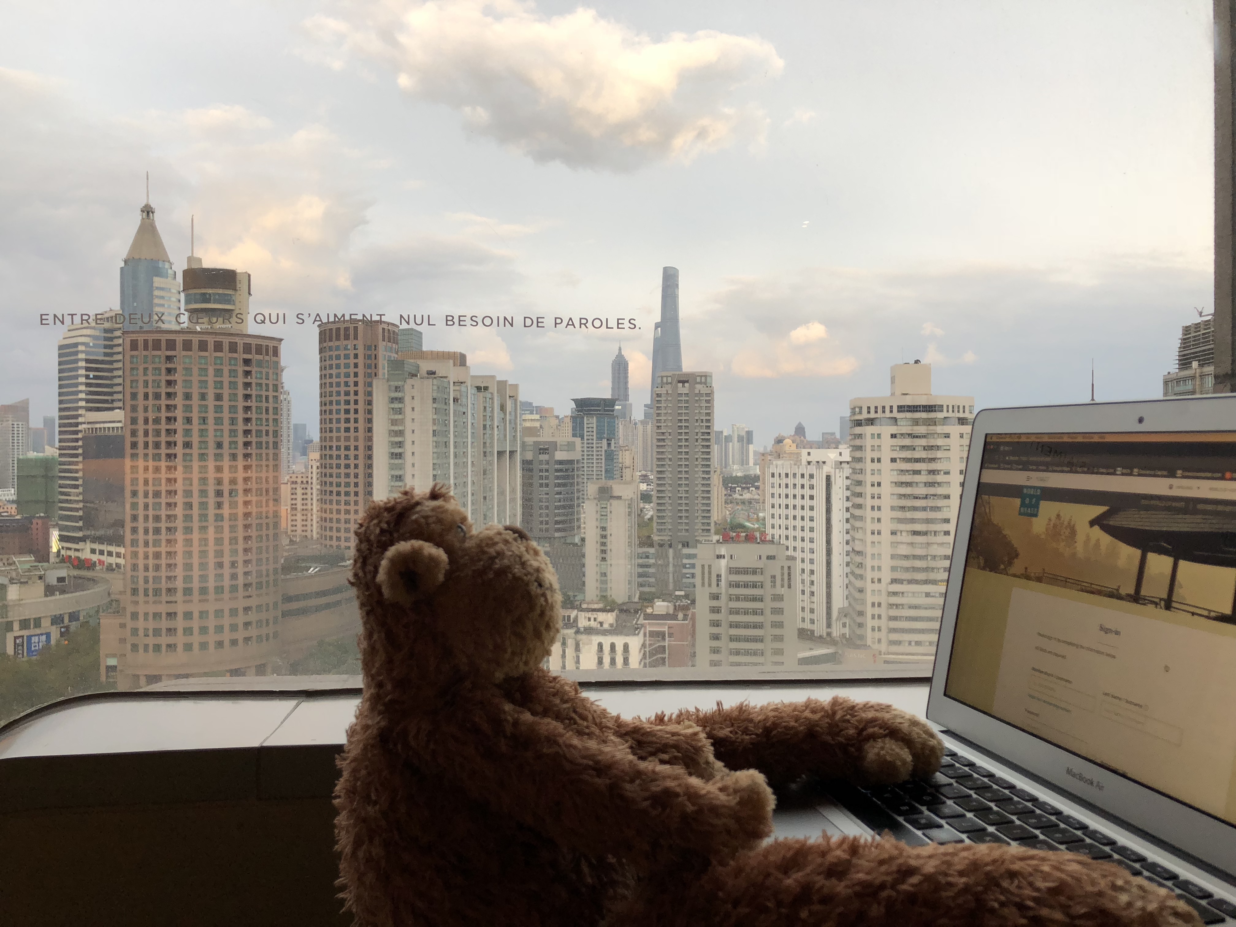 a teddy bear sitting in front of a laptop