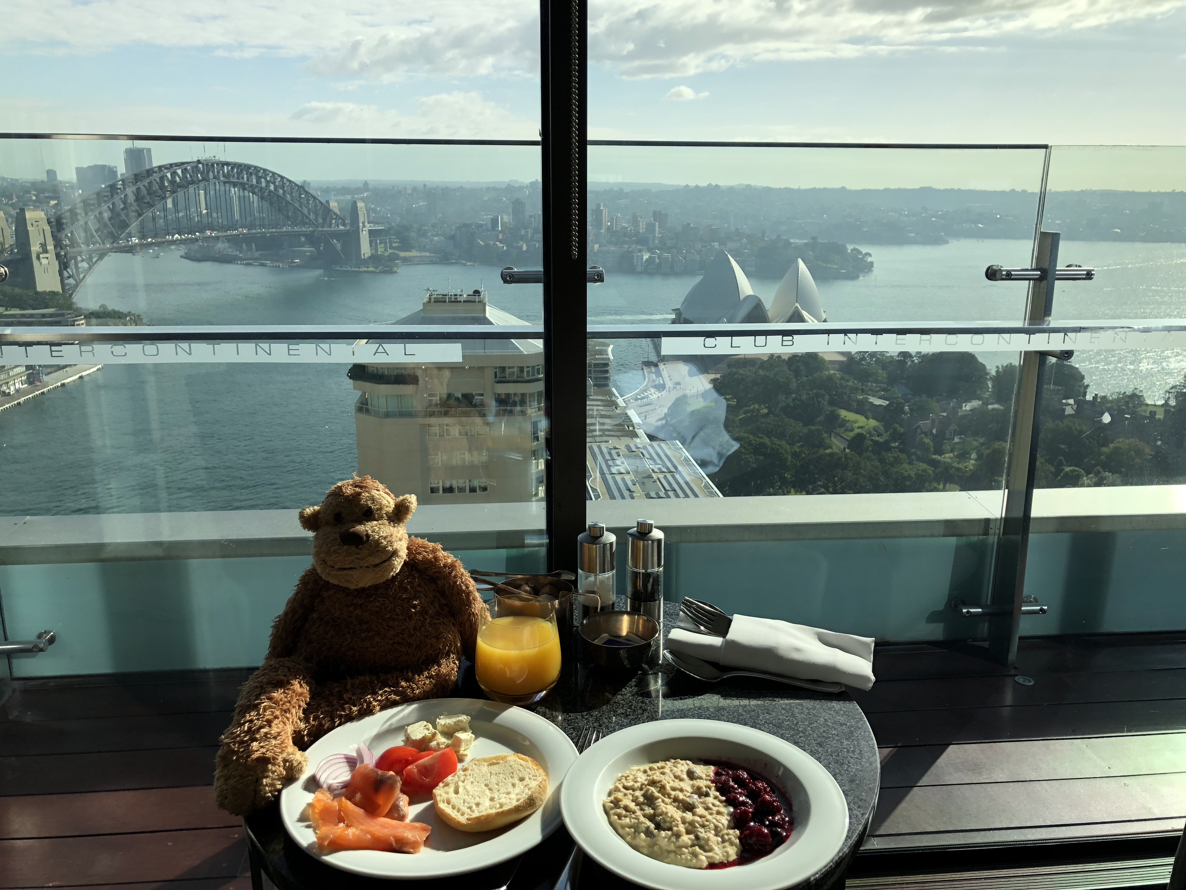 a stuffed monkey sitting at a table with food and drinks