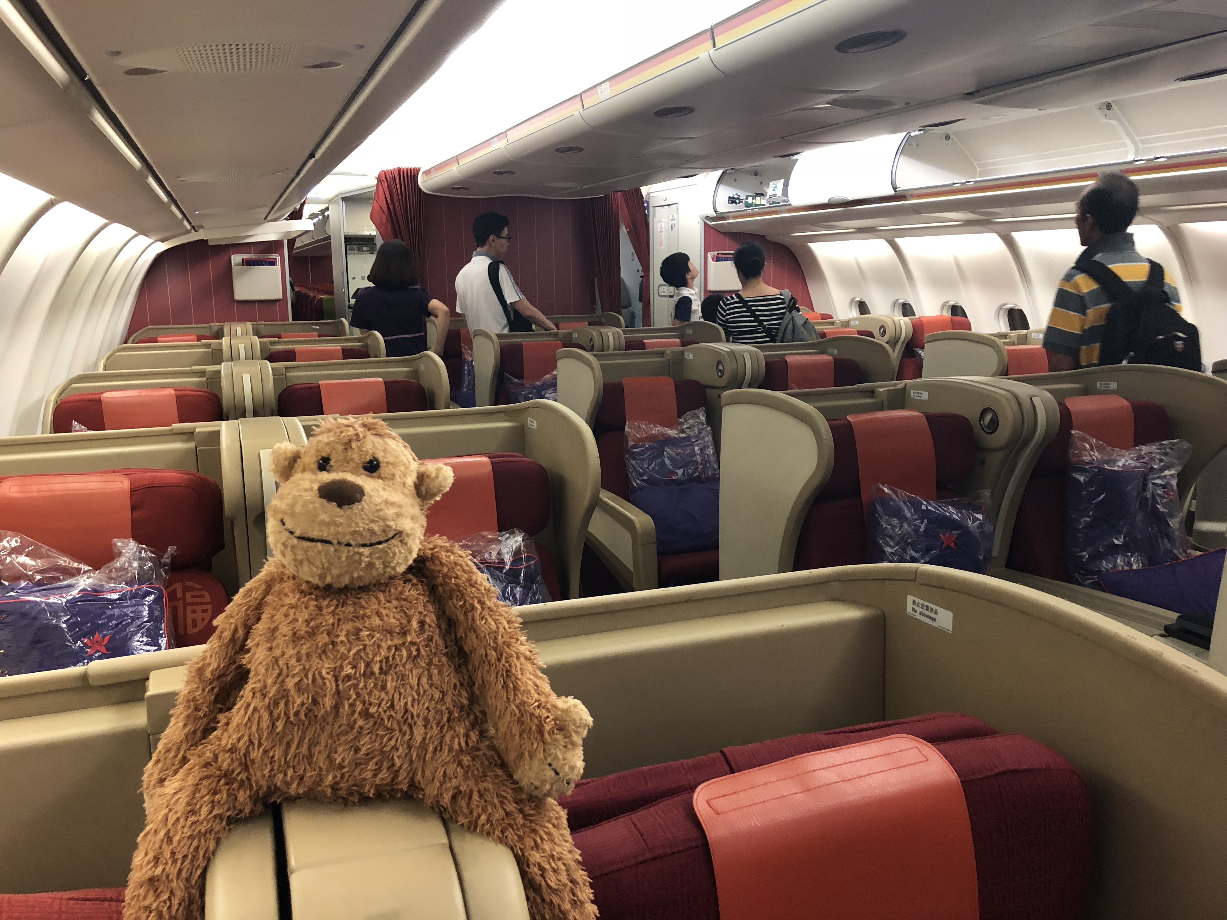 a stuffed monkey sitting on a seat in an airplane