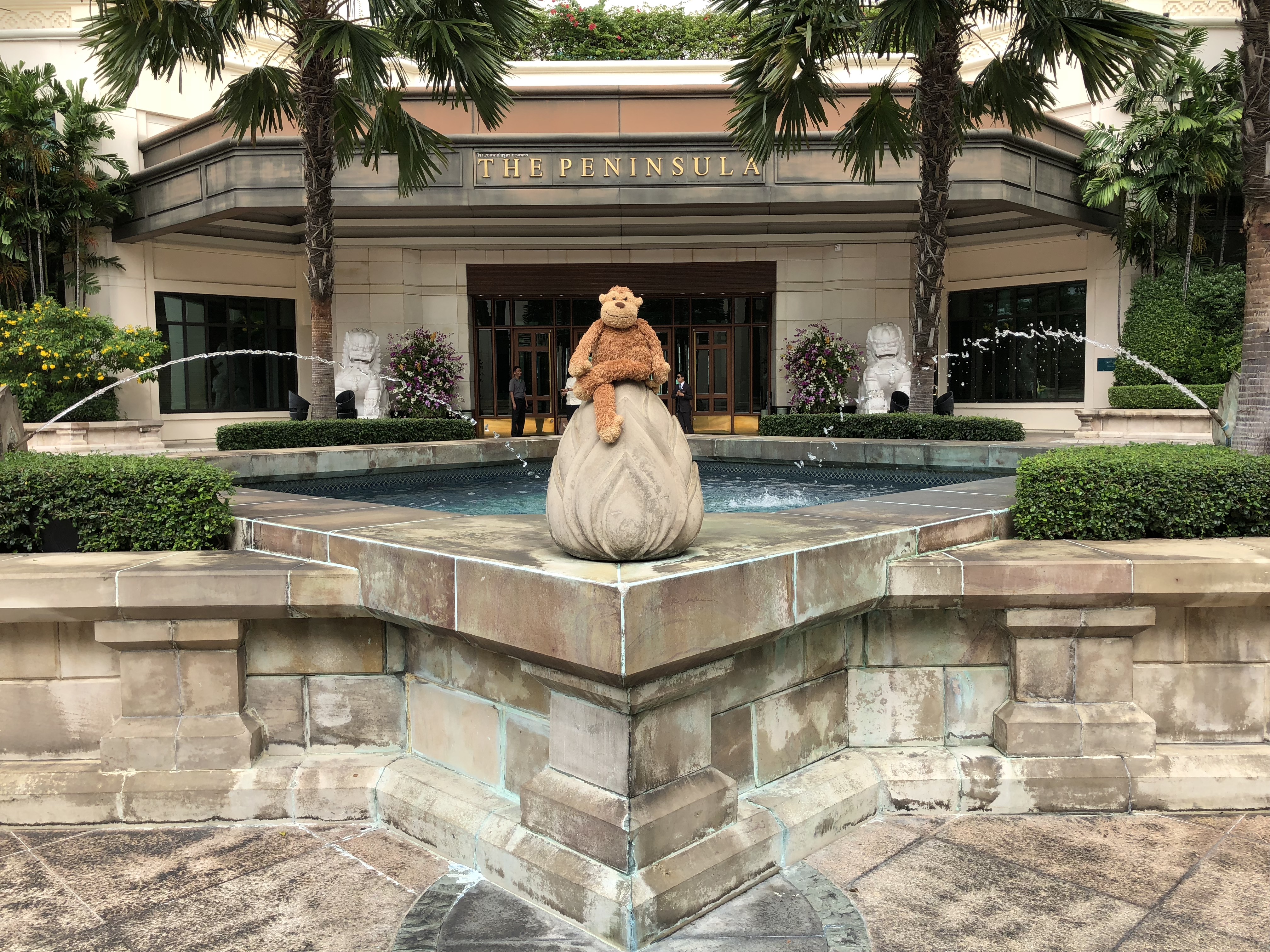 a statue of a teddy bear on a stone object in front of a building