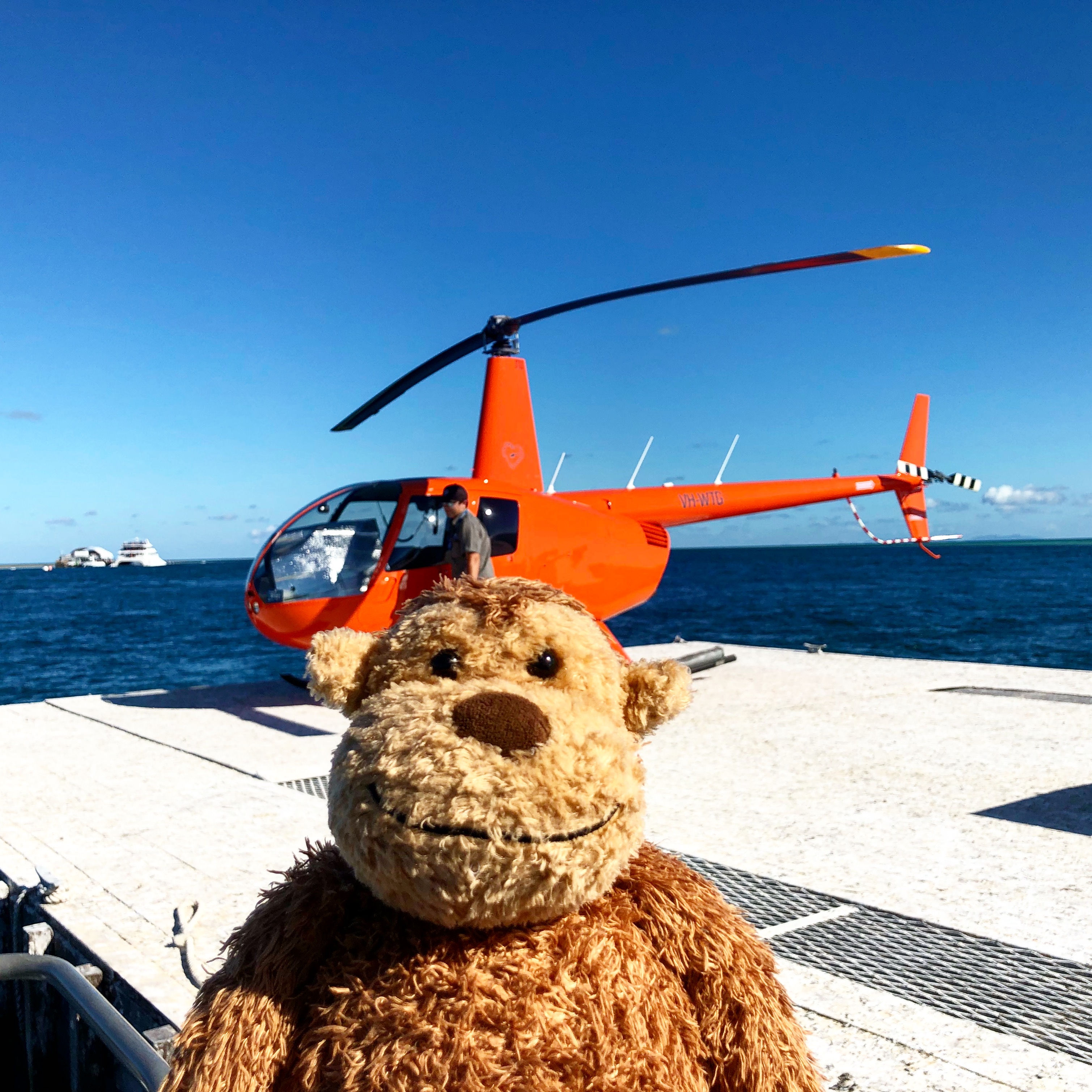 a stuffed animal on a dock with a helicopter in the background
