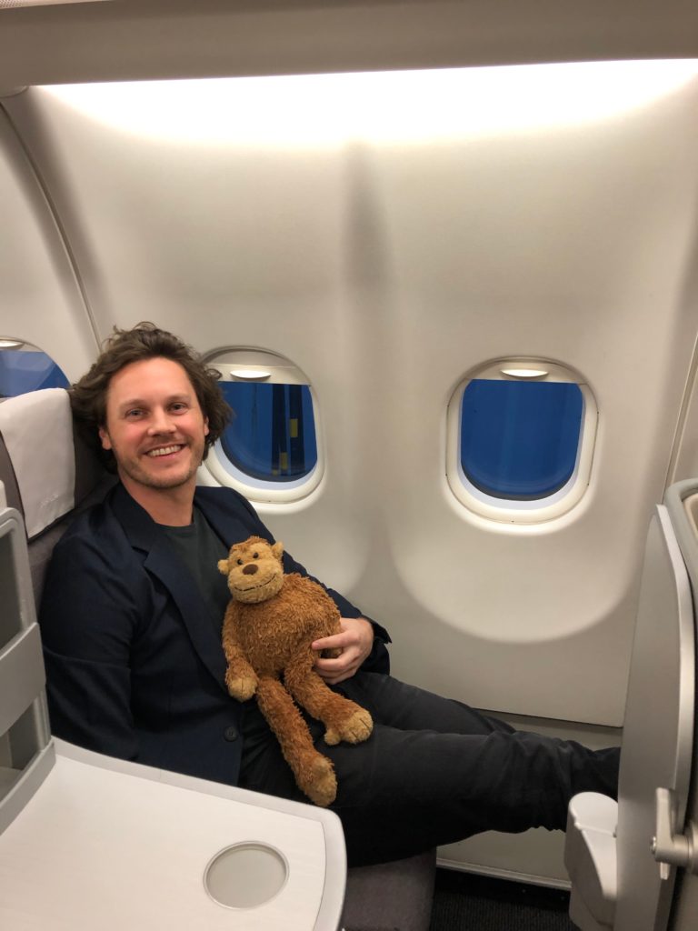 a man sitting in an airplane holding a stuffed animal