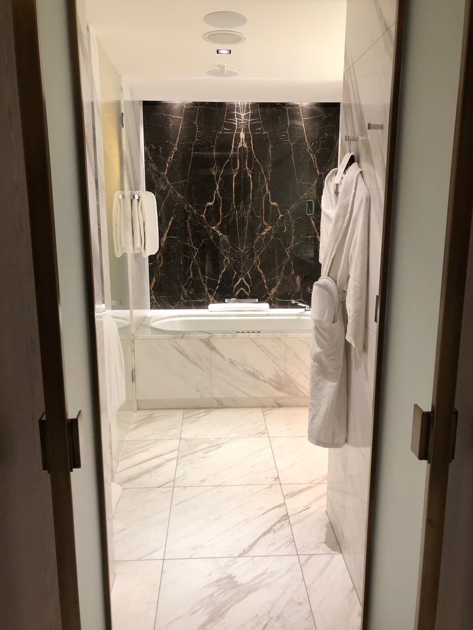 a bathroom with marble tile floor and white bathtub