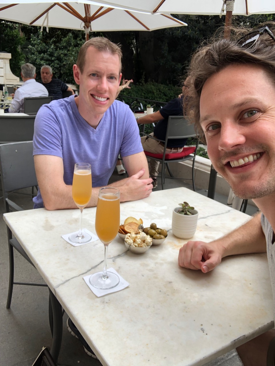 two men sitting at a table with drinks