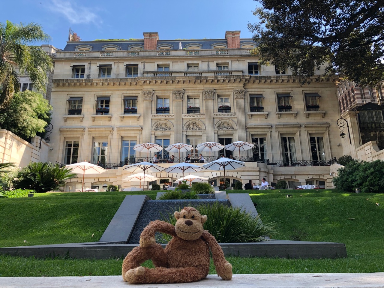 a stuffed animal sitting on a bench in front of a large building