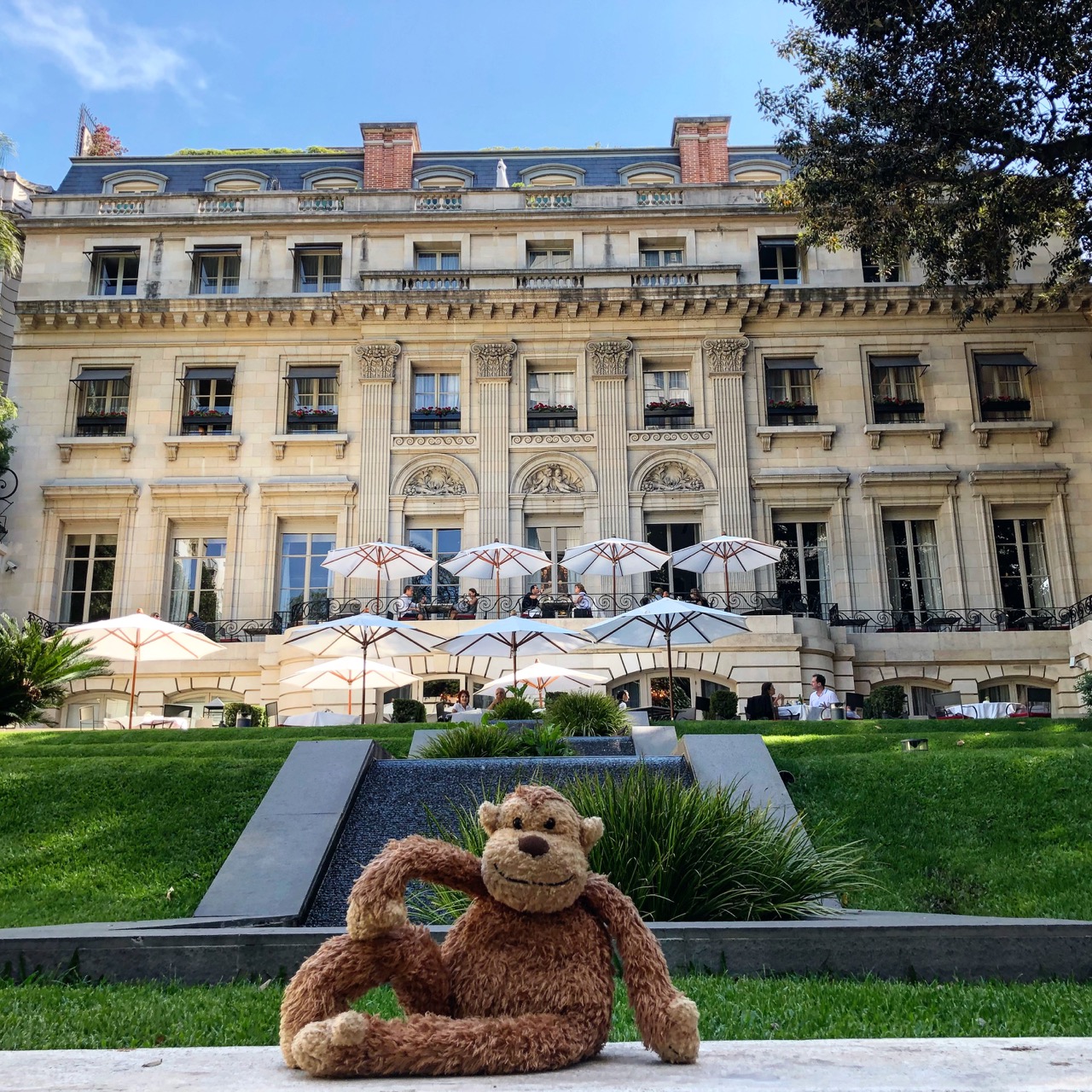 a stuffed animal sitting on a ledge in front of a large building