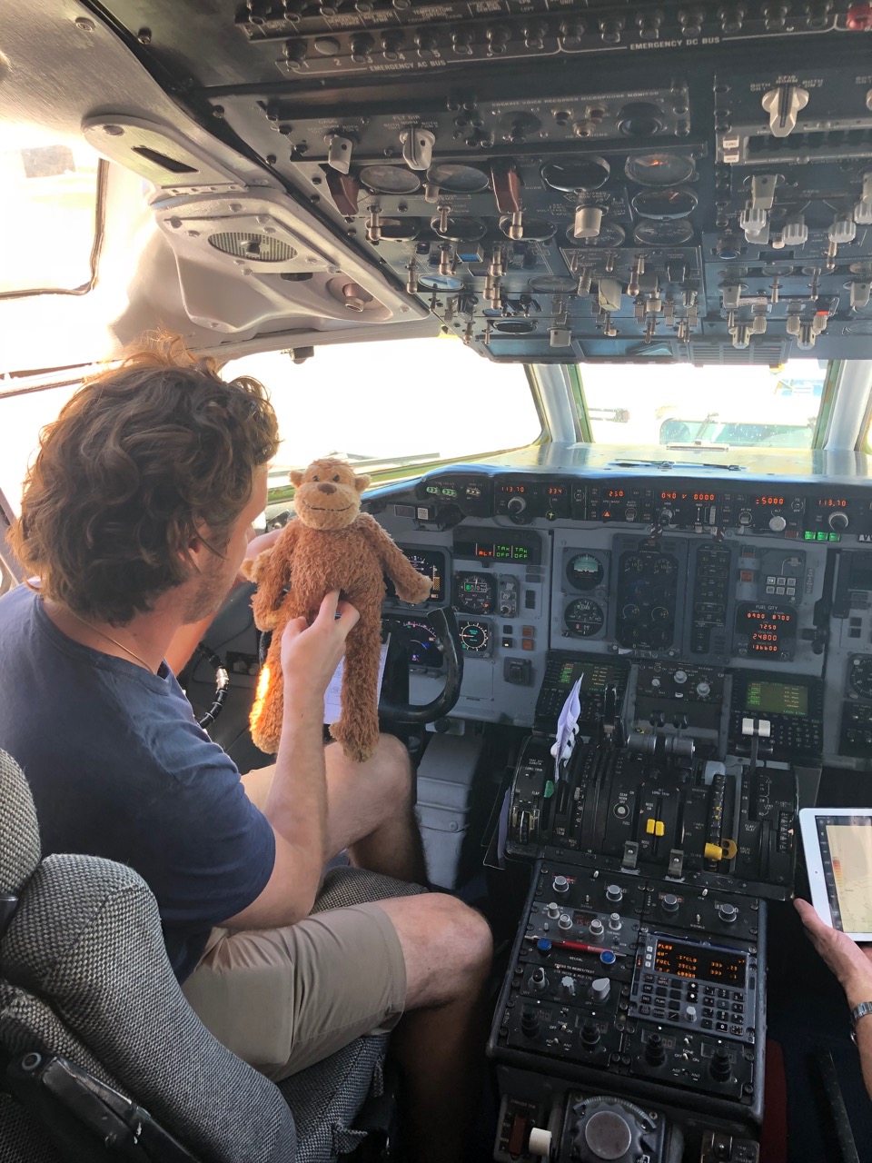 a man holding a stuffed animal in a cockpit of an airplane