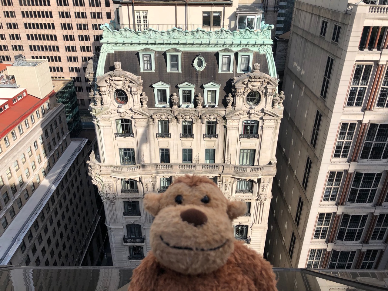 a stuffed monkey on a ledge overlooking a large building