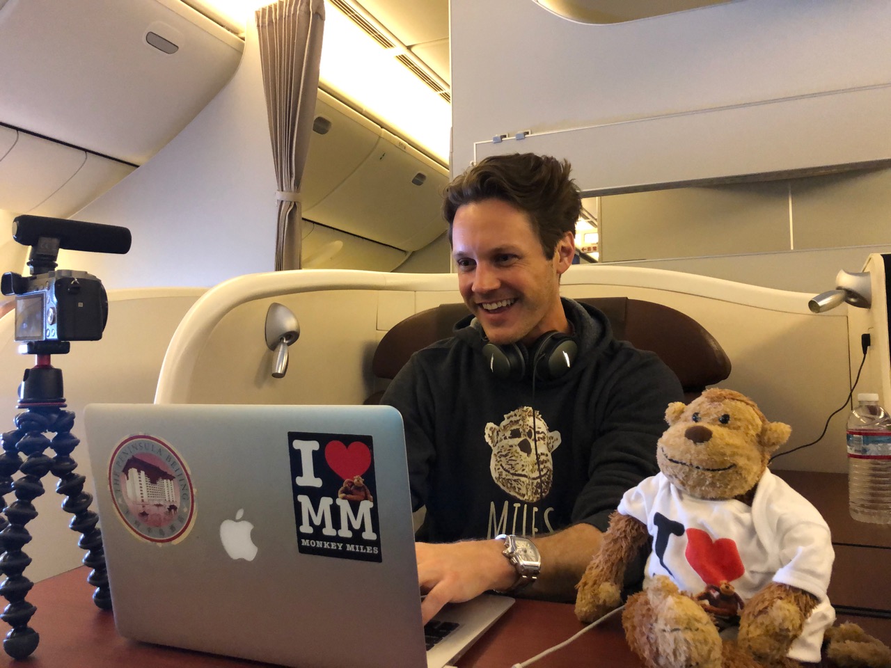 a man sitting at a desk with a laptop and a stuffed animal