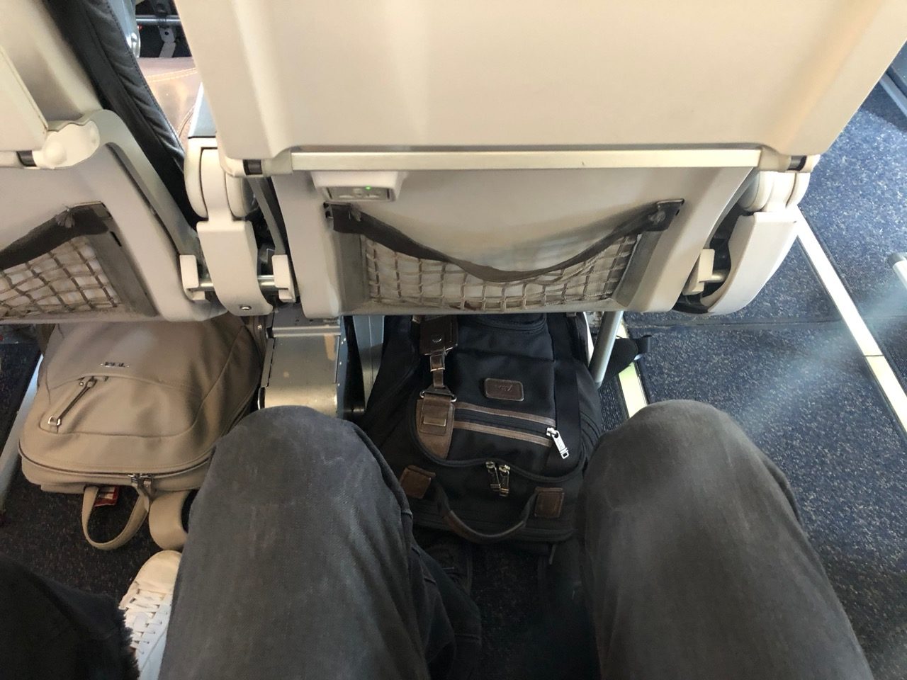 a person's legs and a backpack on a plane