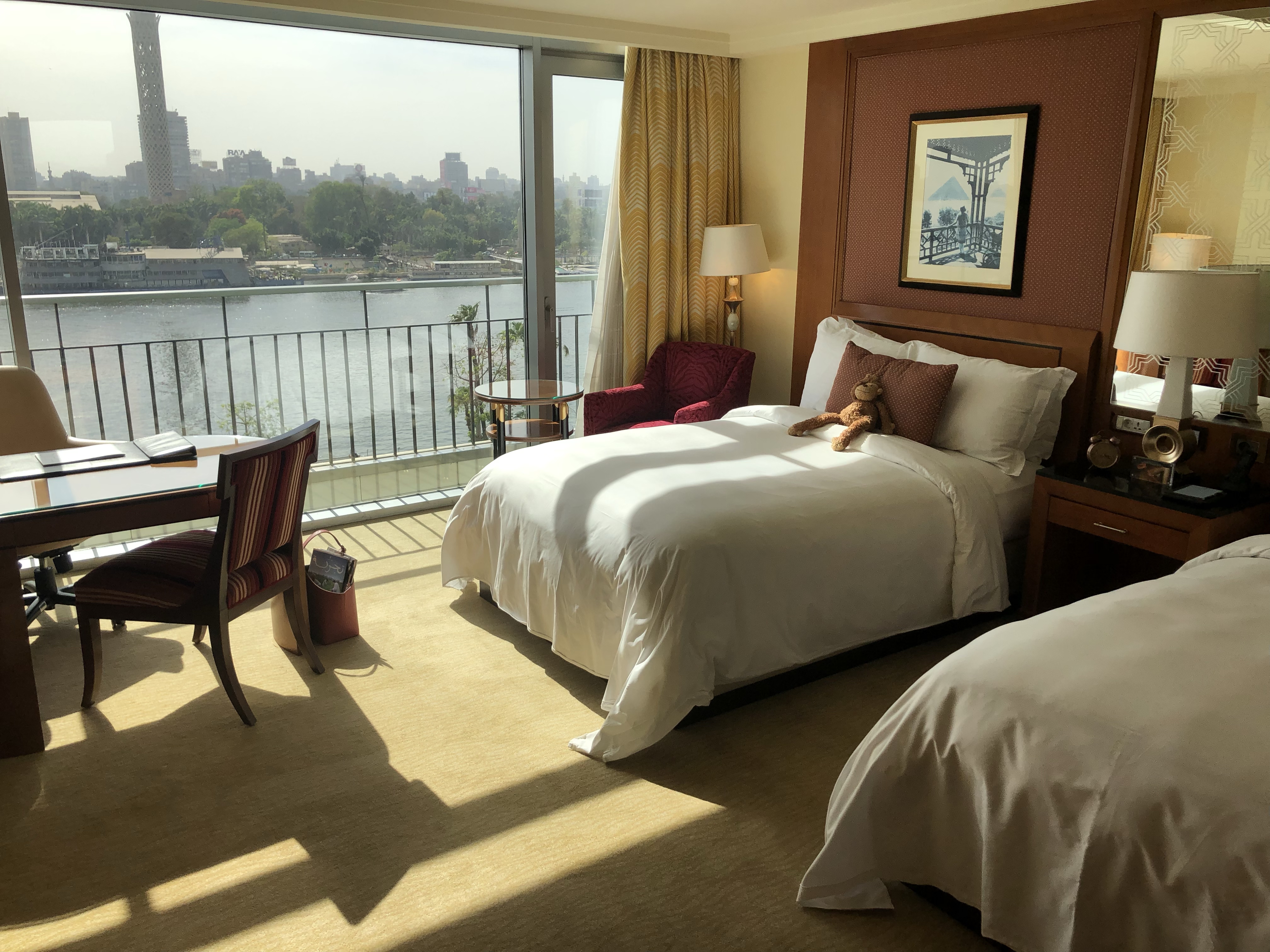 a room with two beds and a balcony overlooking a river