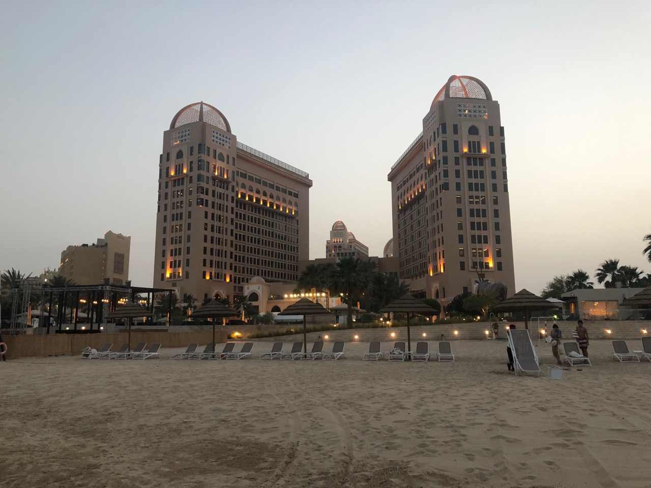 a group of tall buildings with lights on the top and a beach