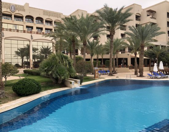 a pool with palm trees in front of a building