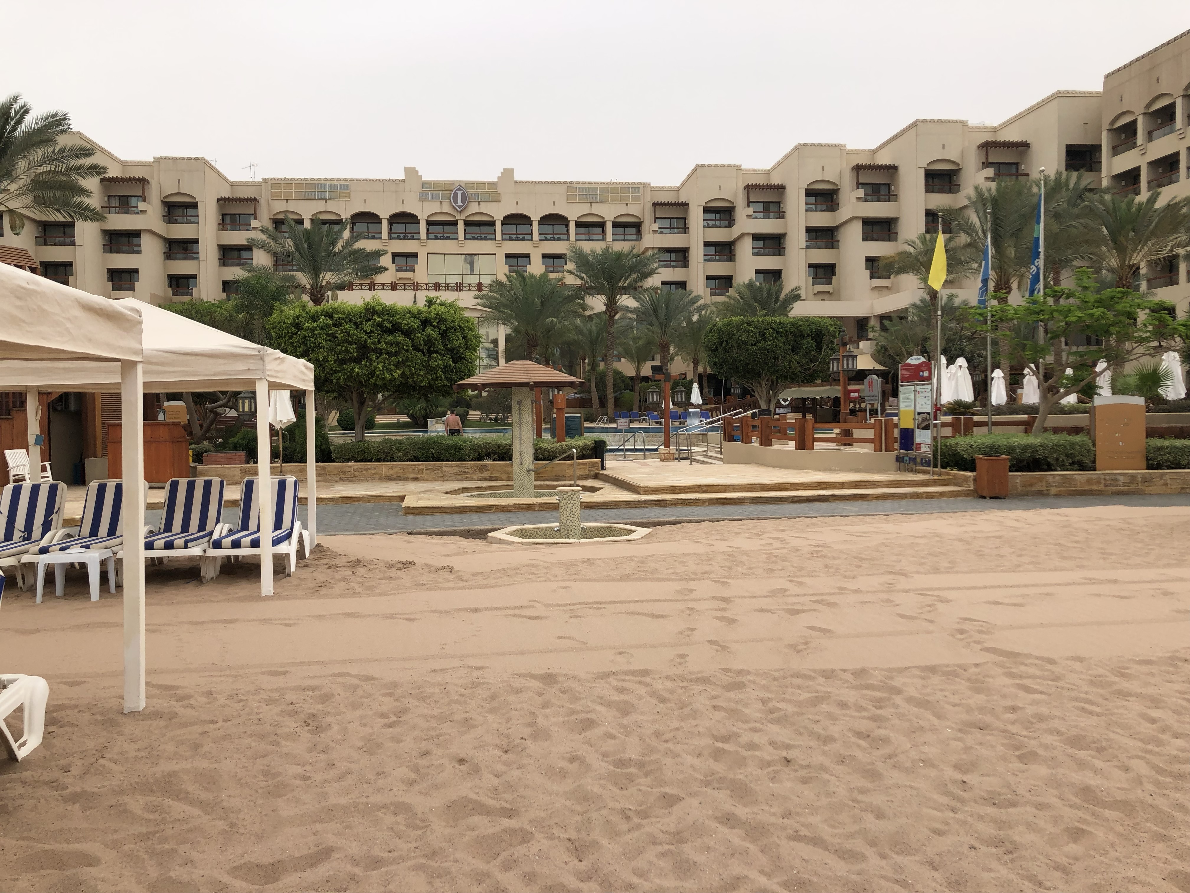 a beach with chairs and a pool in front of a building