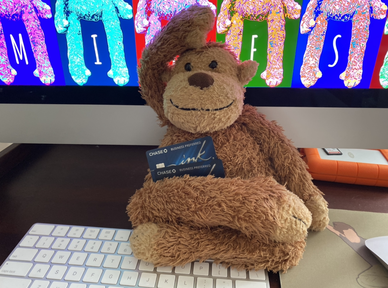 a stuffed monkey holding a credit card