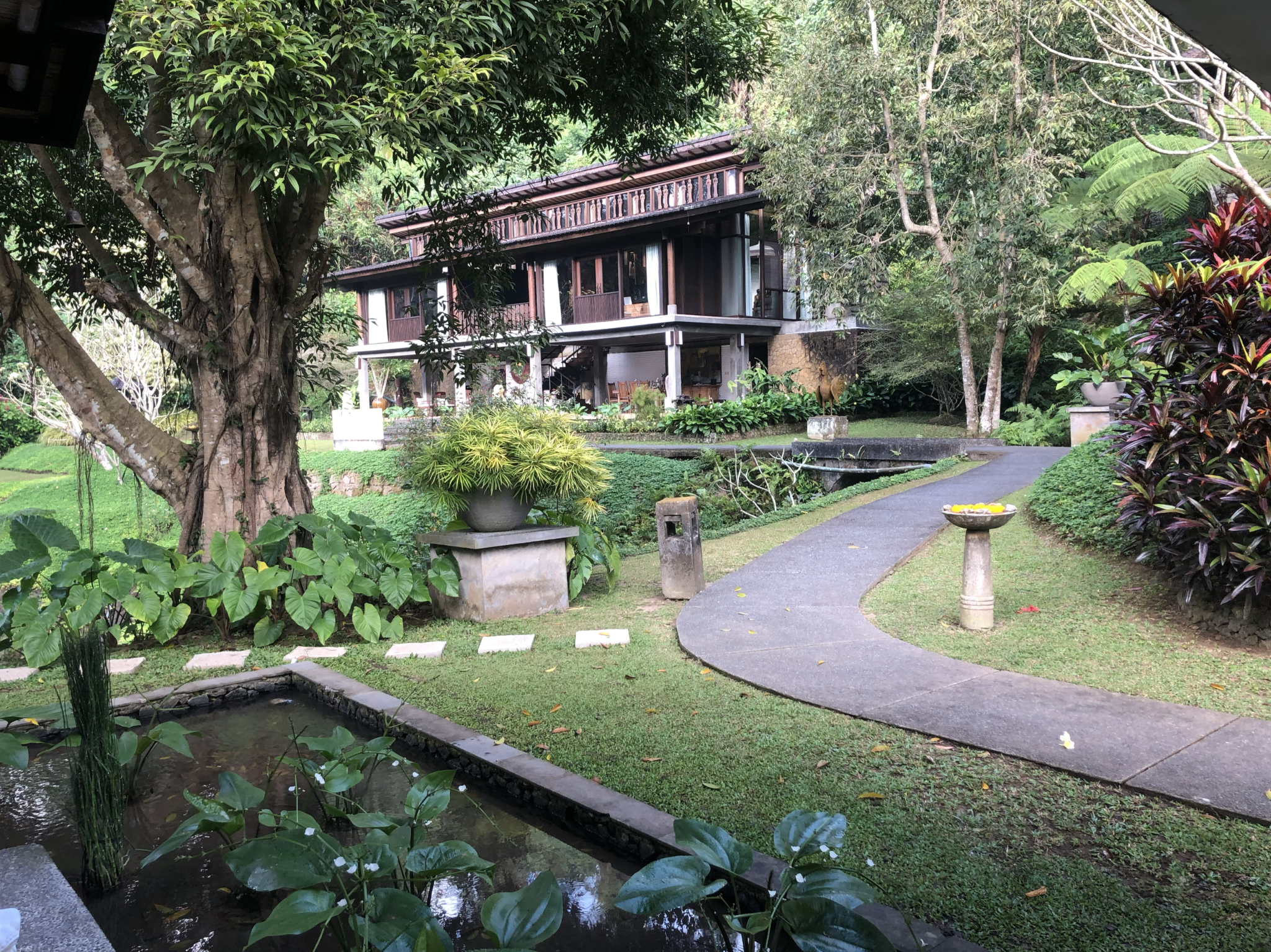 a walkway in a garden with a building and trees