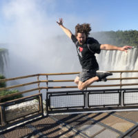 a man jumping in the air with a waterfall in the background