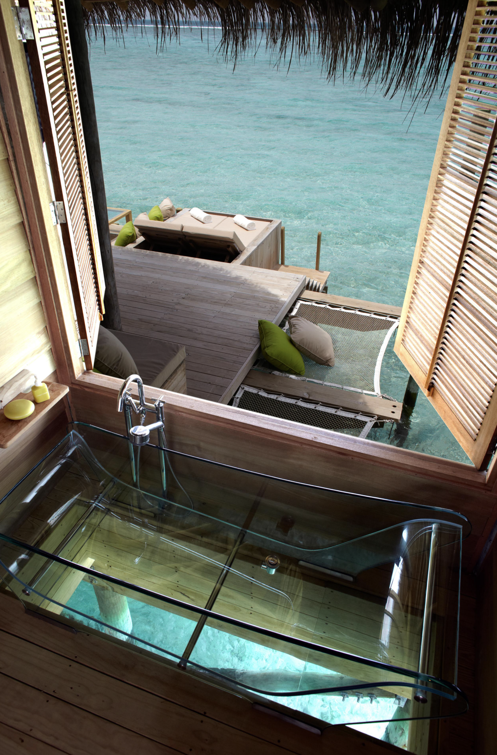 a view from a window of a room with a glass sink and a hammock over water