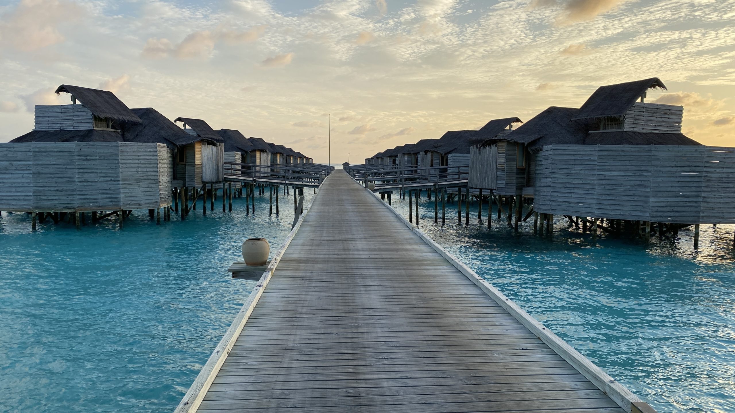 a long wooden walkway leading to a row of huts on stilts